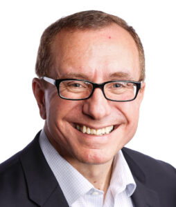 An image of John wearing glasses and a black suit jacket on a white background
