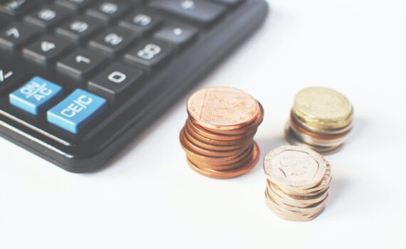 gold colored coins near calculator